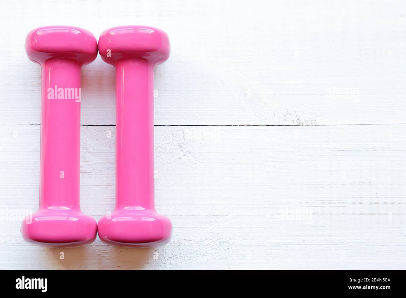 Pink dumbbells for fitness weighing 0.5 kg over a white wooden table Stock Photo