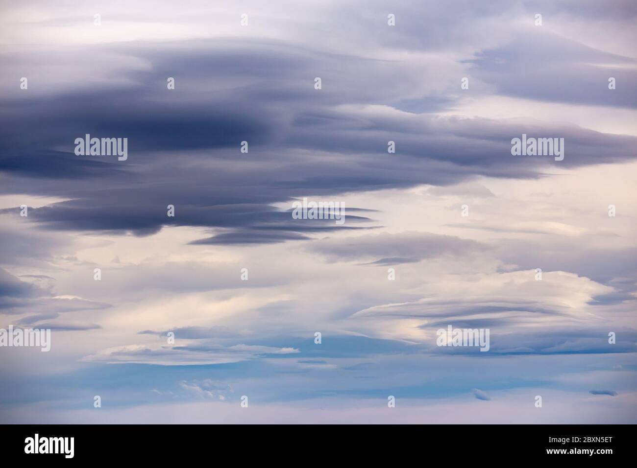 Gloomy layered clouds in cloudy, windy weather with blue gaps Stock Photo