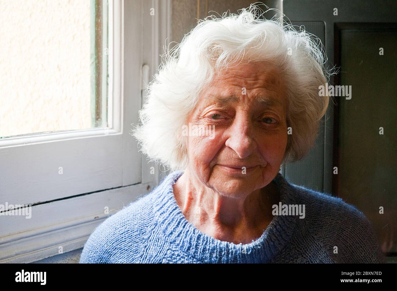 Portrait of elderly woman by the window. Stock Photo