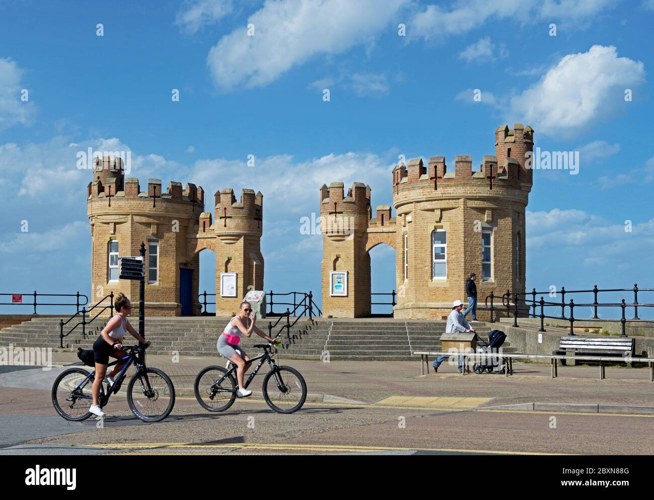 Cyclists passing the castellated pier towers, Withernsea, East Yorkshire, England UK Stock Photo