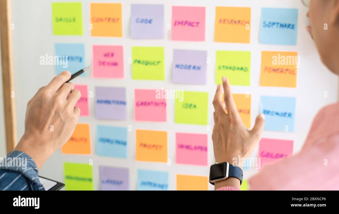 Business people meeting at office and use sticky notes on glass wall in office, diverse employees people group planning work together brainstorm strat Stock Photo