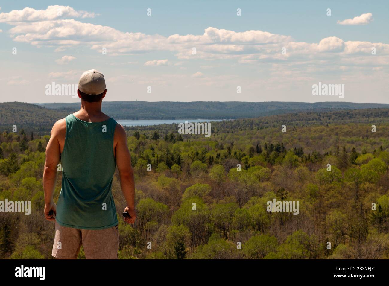 Rear View Of Man Sitting On Rock Over Landscape Stock Photo - Alamy