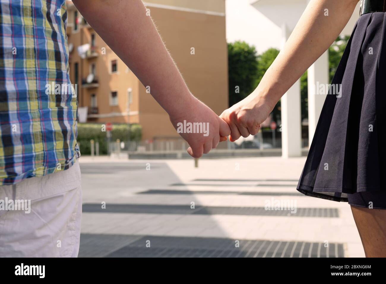 Closeup of the hands of a boy and girl walking on the street holding hands. Boy and girl walking on the urban street and holding hands. Concept of fam Stock Photo