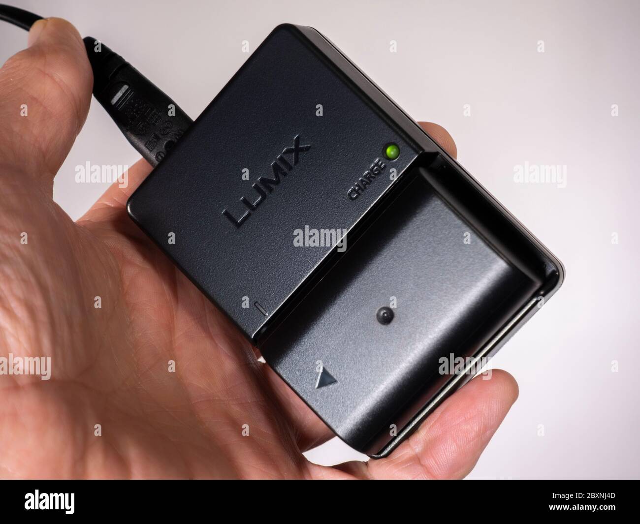 Isolated shot of a man's hand holding a Panasonic Lumix camera battery  charger, with the green charging light activated, and camera battery  inserted Stock Photo - Alamy