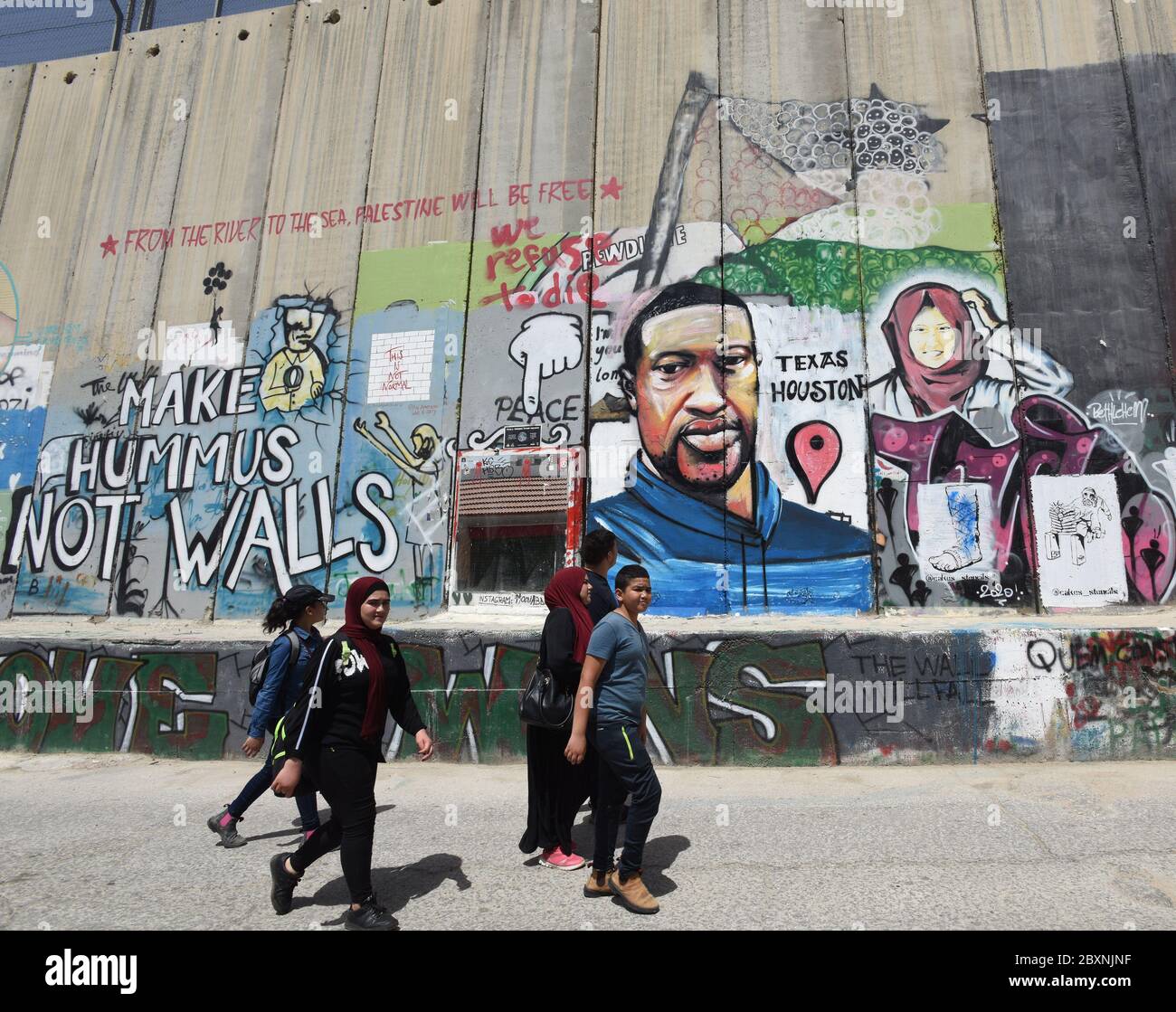 Bethlehem, West Bank. 08th June, 2020. Palestinians walk past a graffiti mural of the late George Floyd on the Israeli separation wall in Bethlehem, West Bank, on Monday, June 8, 2020. Floyd, 46, an unarmed African American, died on May 25, in Minneapolis, Minnesota, after a white police officer Derek Charvin forcefully knelt on his neck for nearly nine minutes while Floyd pleaded that he couldn't breathe. Photo by Debbie Hill/UPI Credit: UPI/Alamy Live News Stock Photo