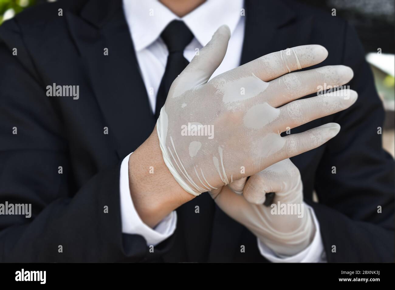 Close up of businessman wearing white latex gloves. Concept for protection health care from corona virus or covid-19 at work. Stock Photo