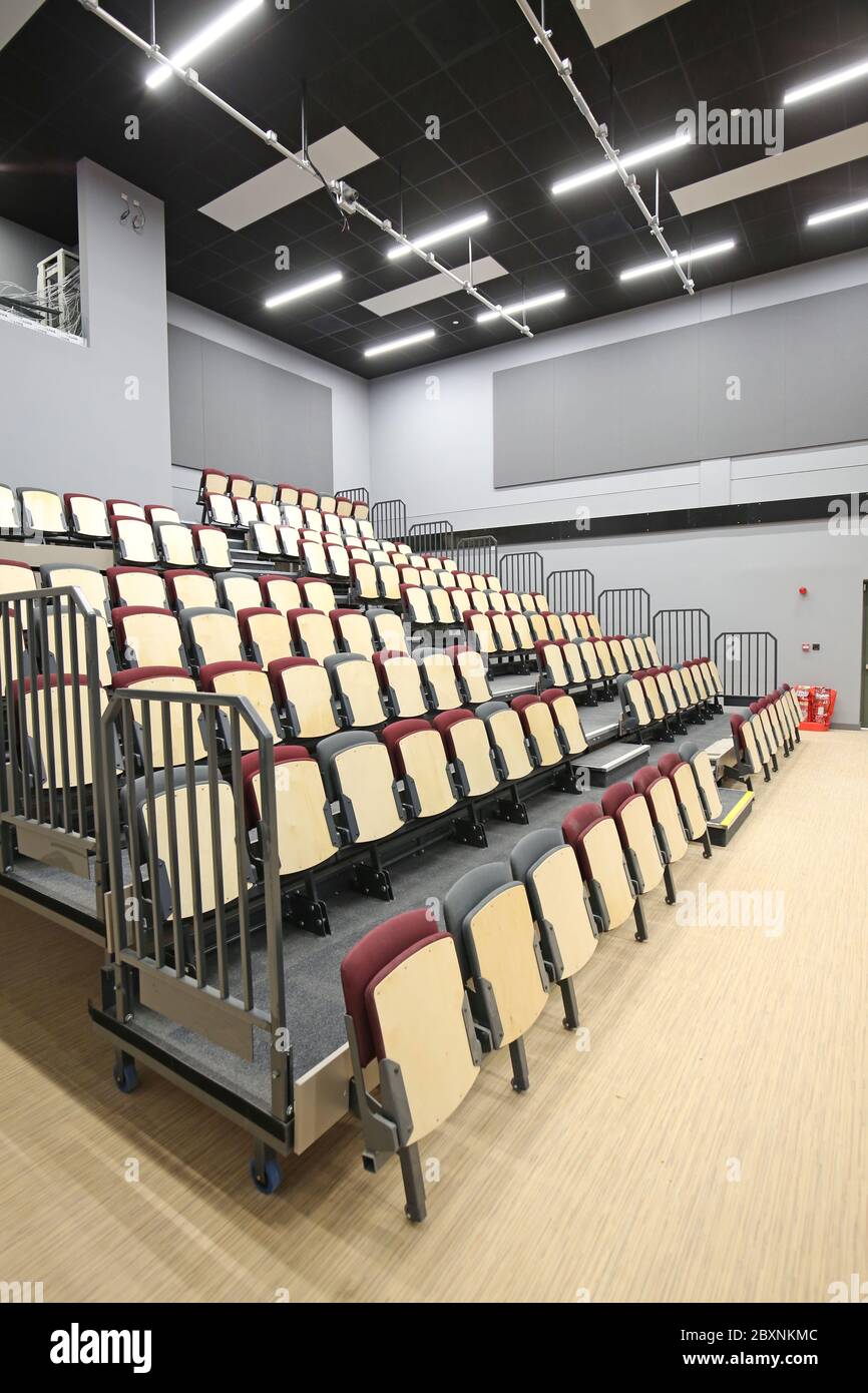 Retractable bleacher seating in a newly built school hall in south London, UK. Shows system fully extended giving 9 rows of tiered seating. Stock Photo