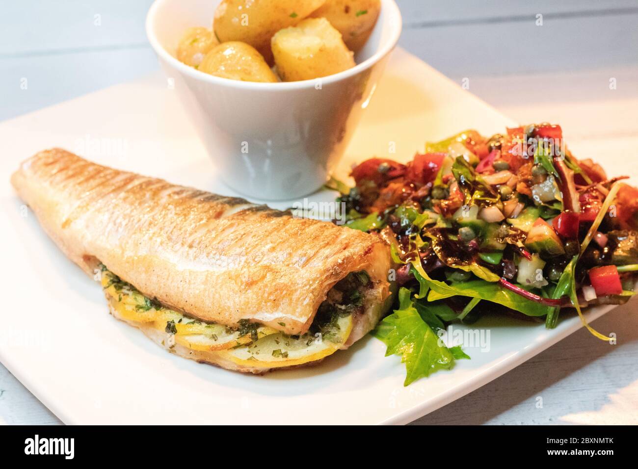 Whole baked sea bass with baby new potatoes Stock Photo Alamy