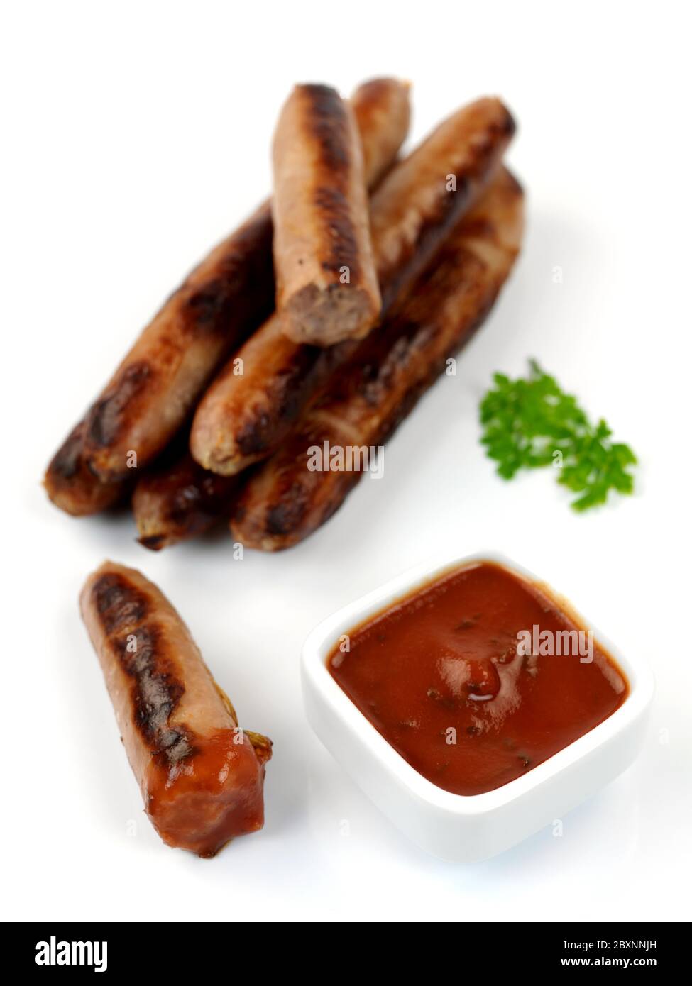 Cooked pork Sausages on a cork board isolated against a white background Stock Photo