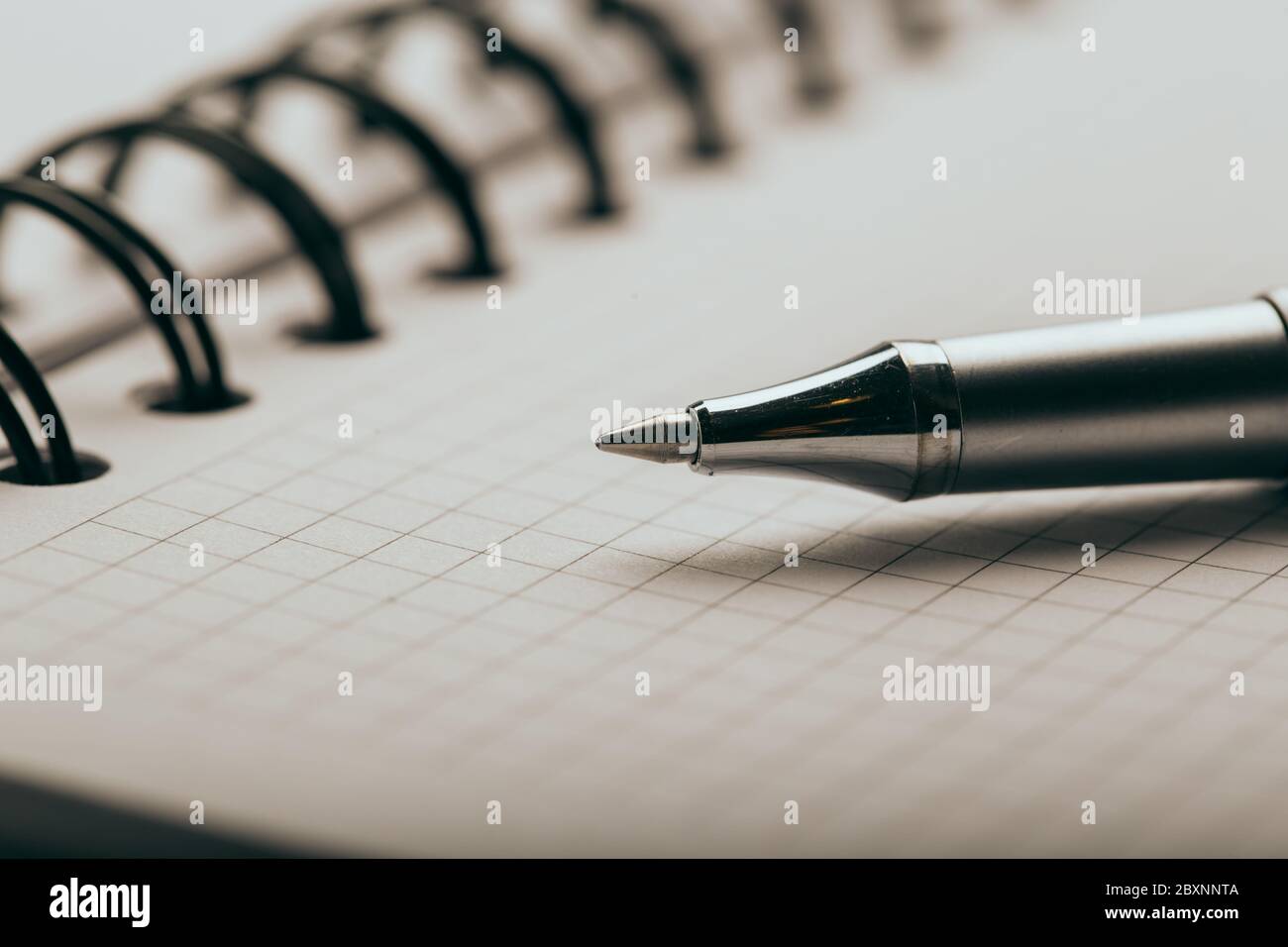 Opened notepad in a cage with an automatic plastic ballpoint pen close-up. Stock Photo