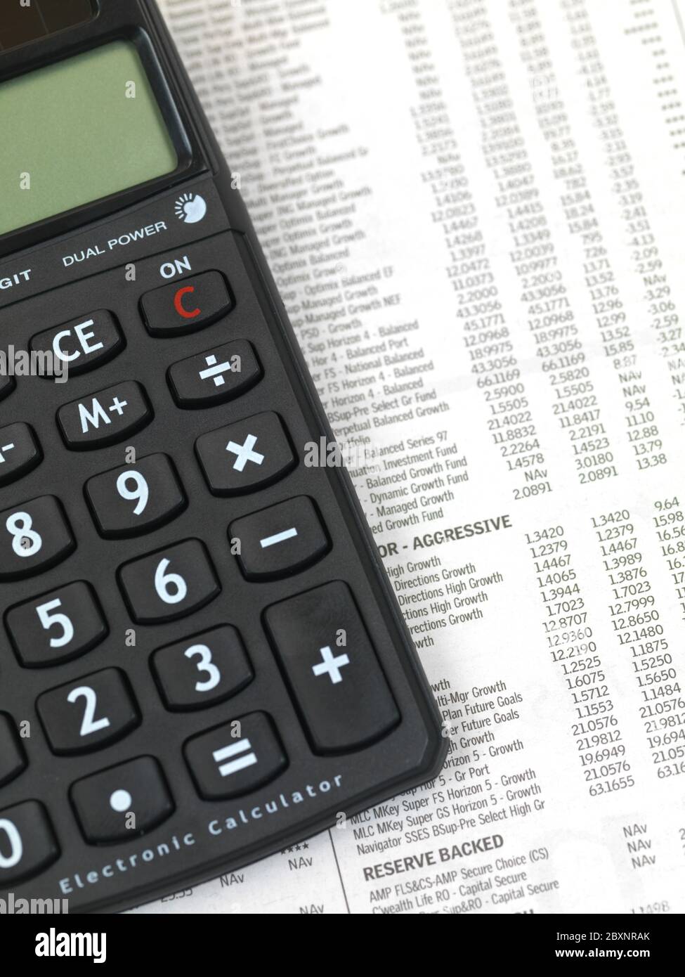 Calculating finances using a financial newspaper Stock Photo