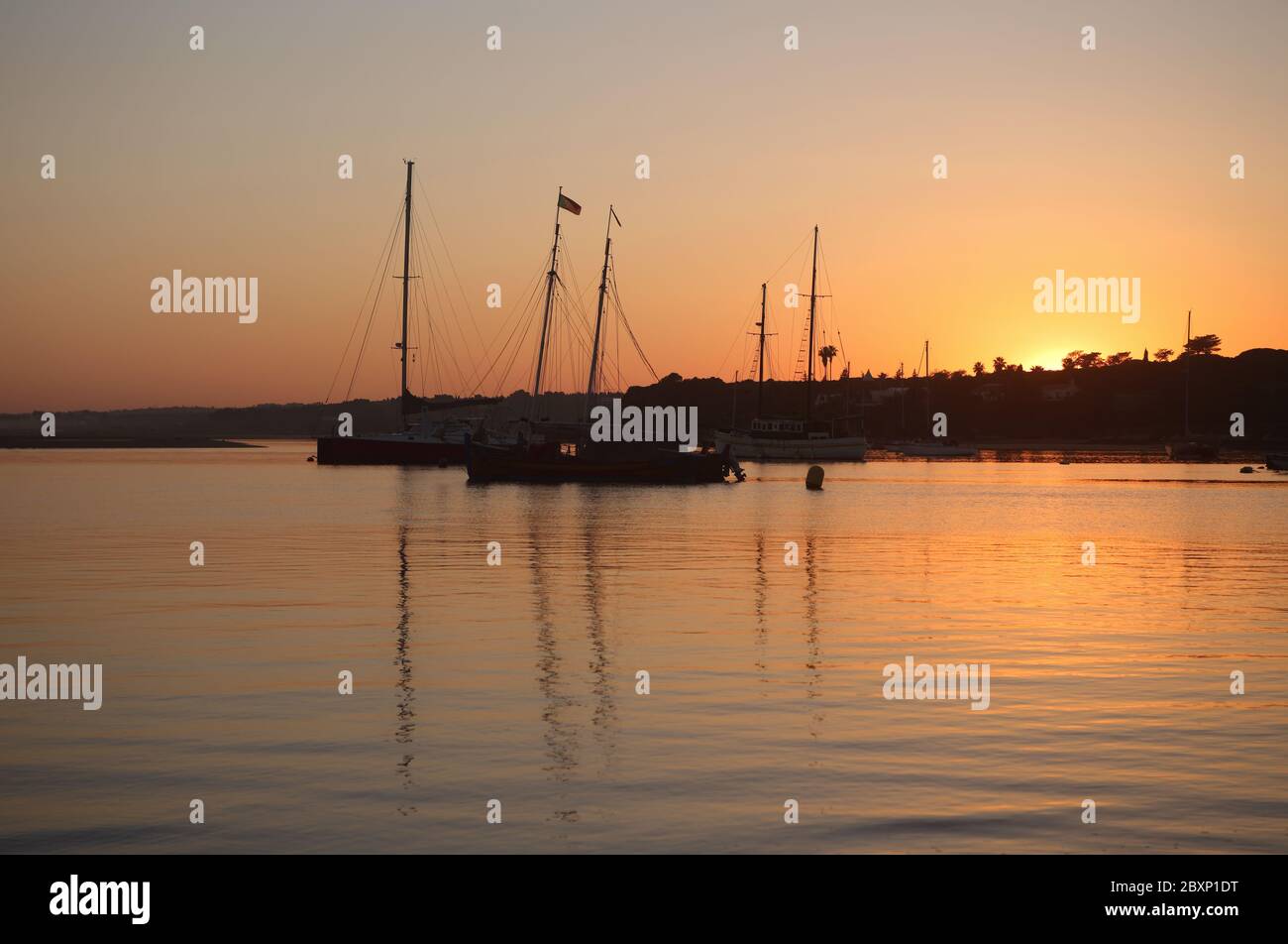 Portugal, Algarve, Portimao. Yachts and traditional boats moored in the Bay of Alvor at sunset. Alvor is a picturesque village and tourist resort. Stock Photo