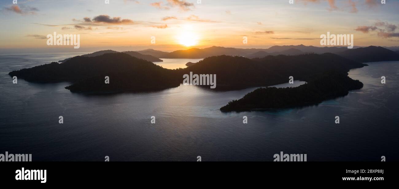 The sun rises over the amazing islands of Raja Ampat, Indonesia. This remote, tropical region is known for its extremely high marine biodiversity. Stock Photo