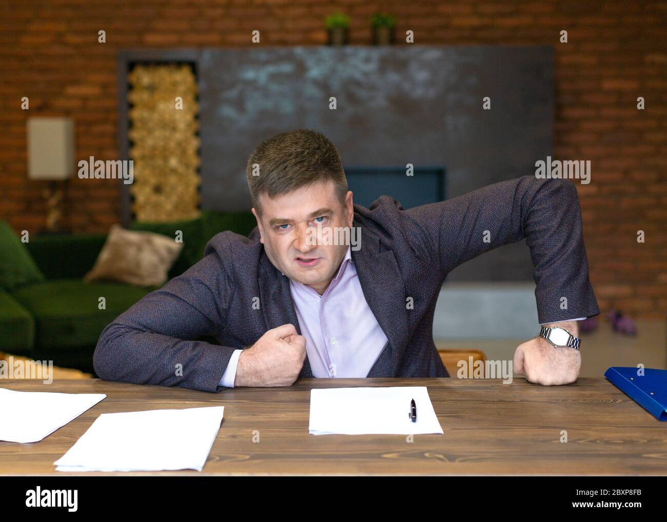 Portrait of an angry middle-aged businessman leaning on his desk. Business concept. Stock Photo