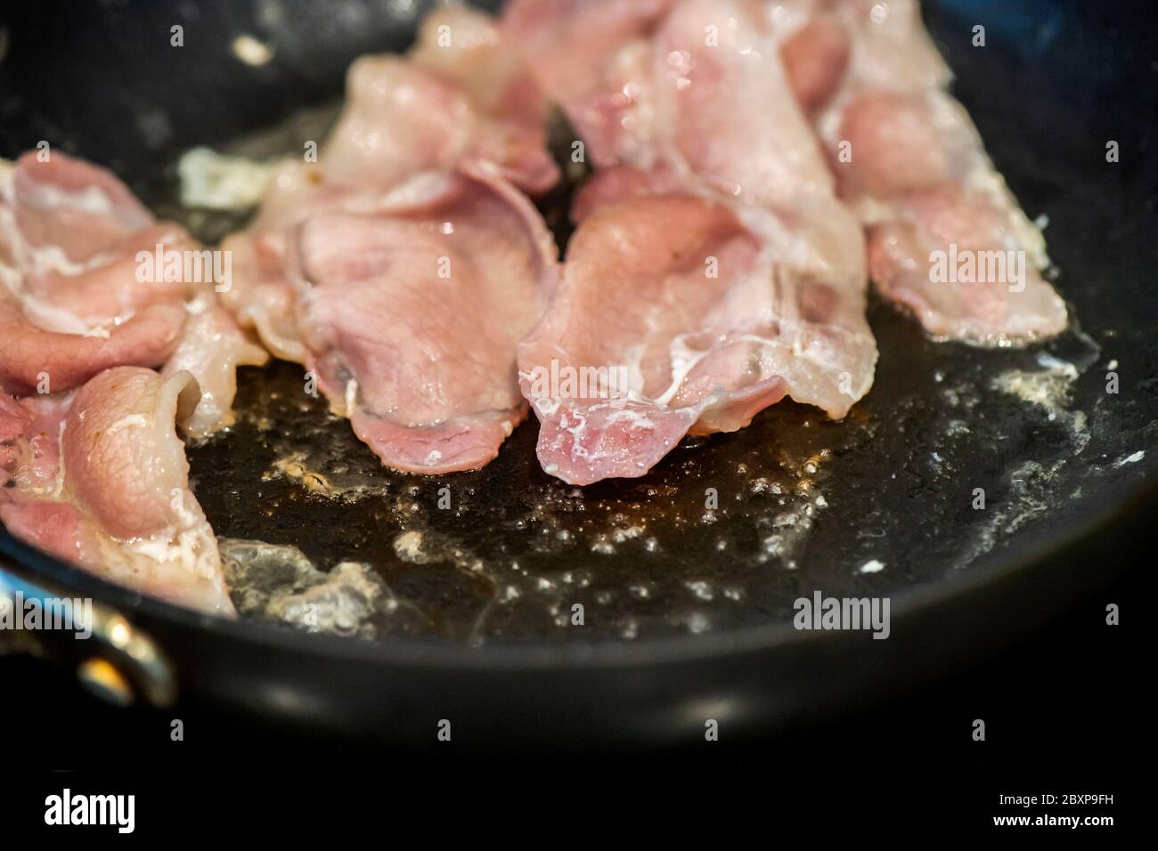 Fat is released as Back Bacon fries in a frying pan Stock Photo - Alamy