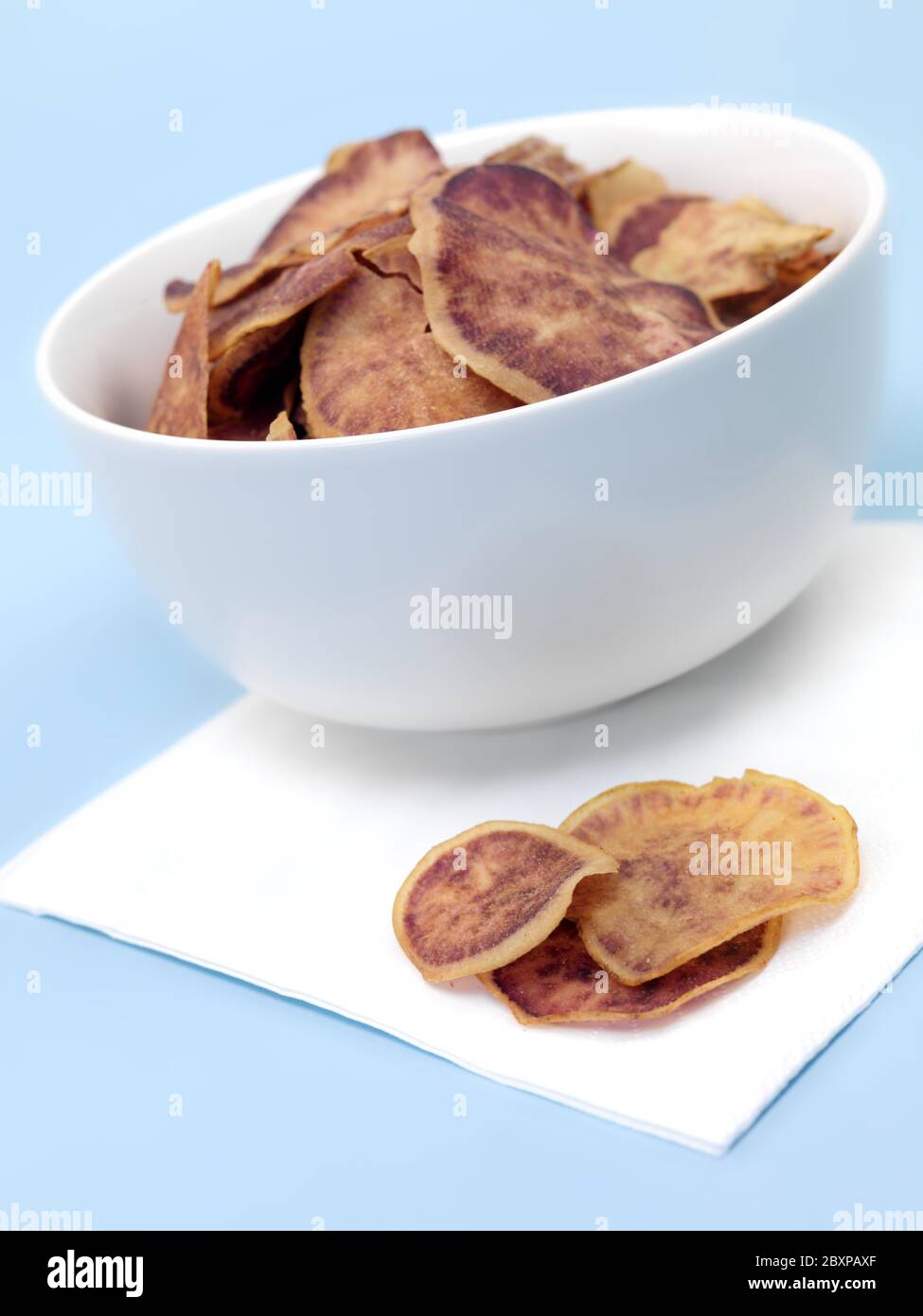 Sweet potato crisps in a bowl isolated against a blue background Stock Photo