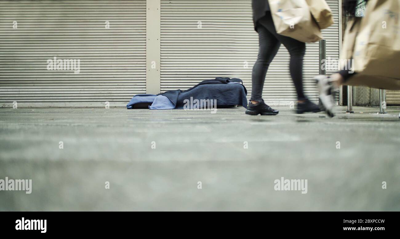 Frankfurt, Germany. June 6th 2020. Homeless person's bed on sidewalk with legs of people walking by. Stock Photo