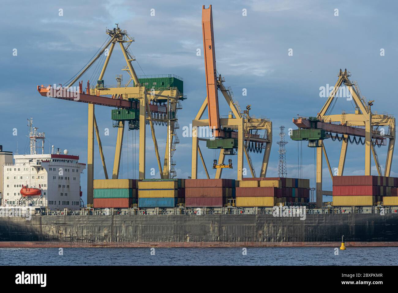 Container ship at unloading in a cargo port. The cargo ship is unloaded ...
