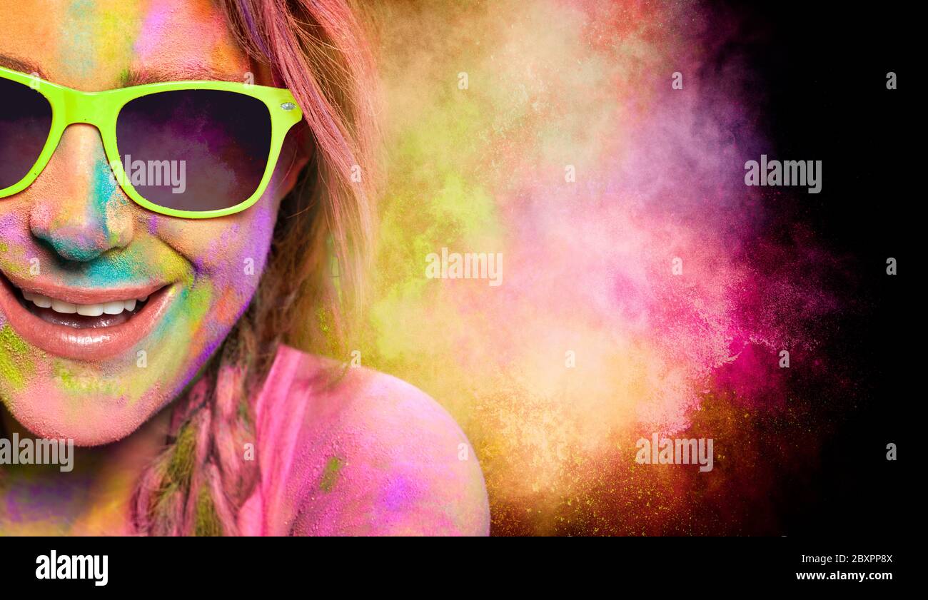 Beautiful young woman in fashionable green sunglasses with her face covered in colorful Holi powder to celebrate the Hindu festival. Close up cropped Stock Photo
