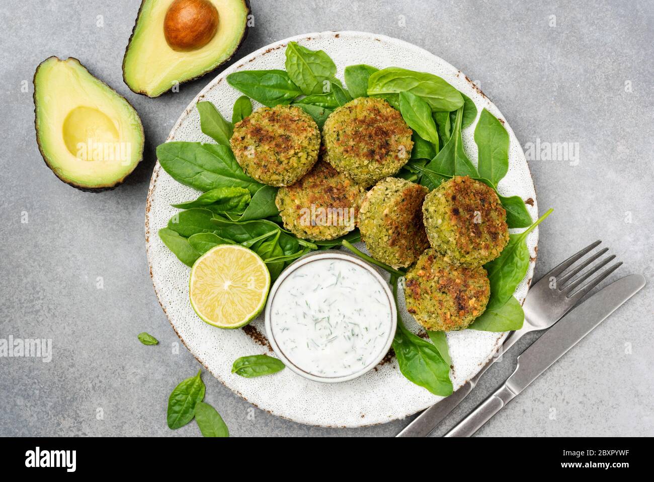 Falafel with spinach served with greek yogurt tzatziki sauce on grey concrete texture background. Top view. Healthy vegetarian appetizer, arabic food Stock Photo