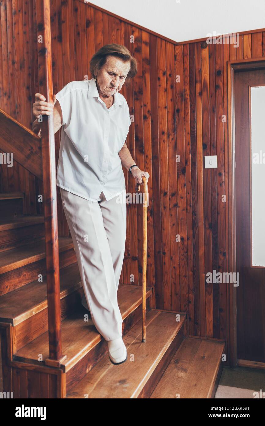 Elderly woman at home using a walking cane to get down the stairs Stock Photo Alamy