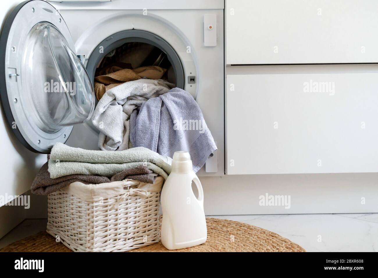 Loading a washing machine and washing clothes. A laundry basket and