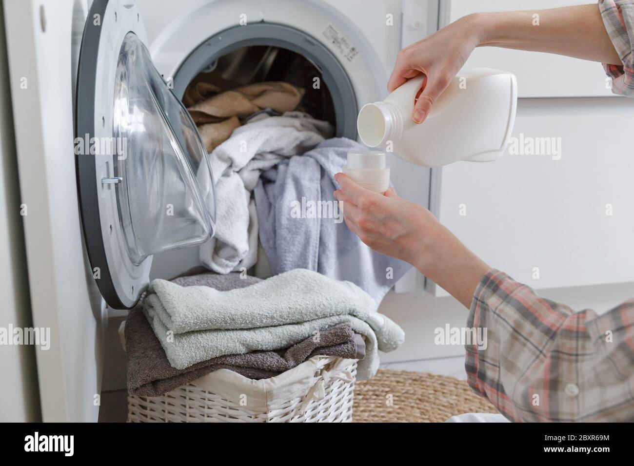 Closeup of liquid gel detergent pouring from the spout of a plastic bottle  into a measuring cup, with dirty washing / laundry in the background Stock  Photo - Alamy