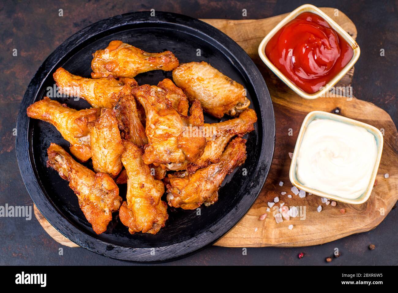Fried chicken dippers in black bucket with sauce on black background