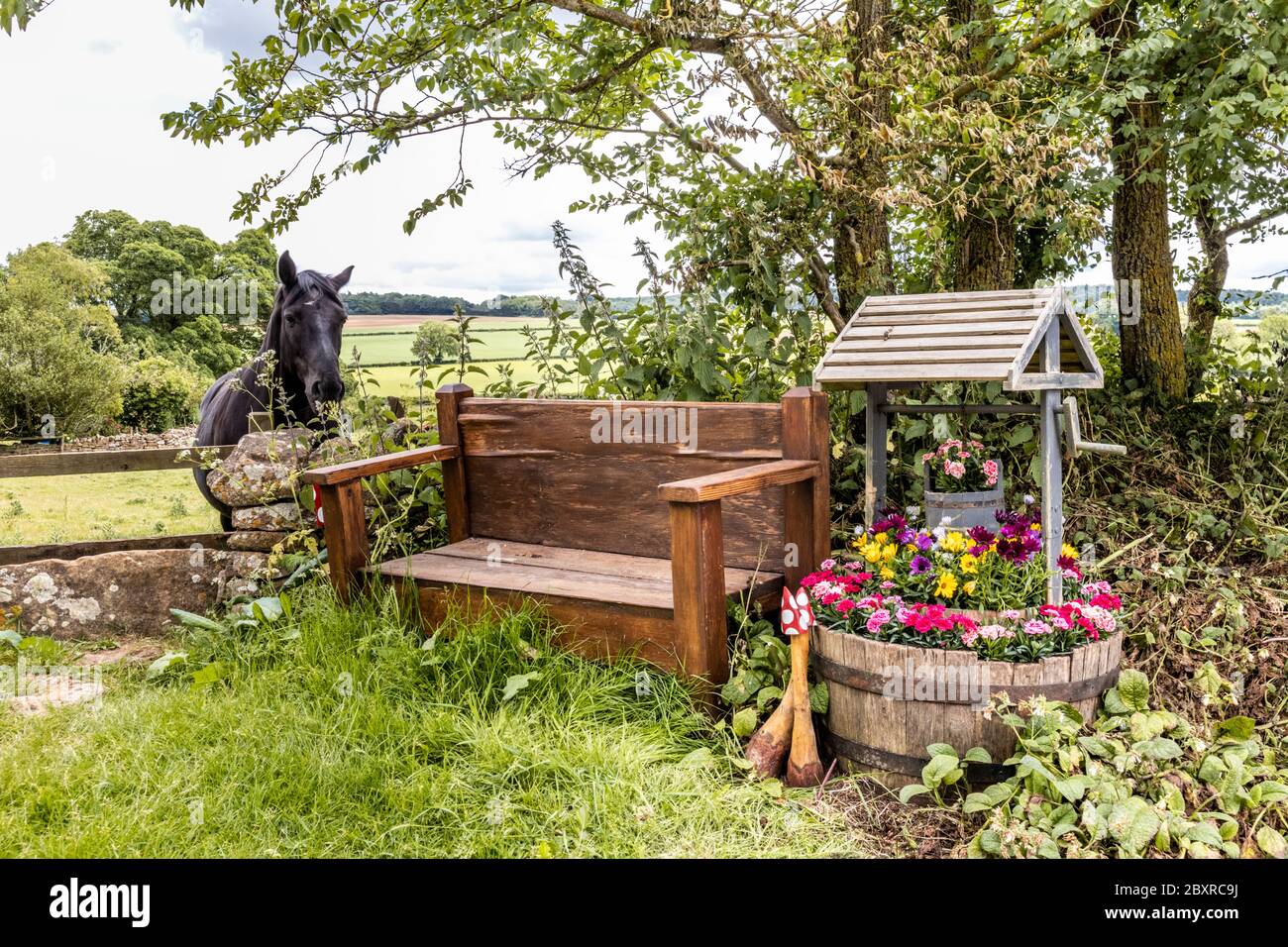 A horse admiring the floral 'wishing well' in the Cotswold hamlet of Taddington, Gloucestershire UK Stock Photo