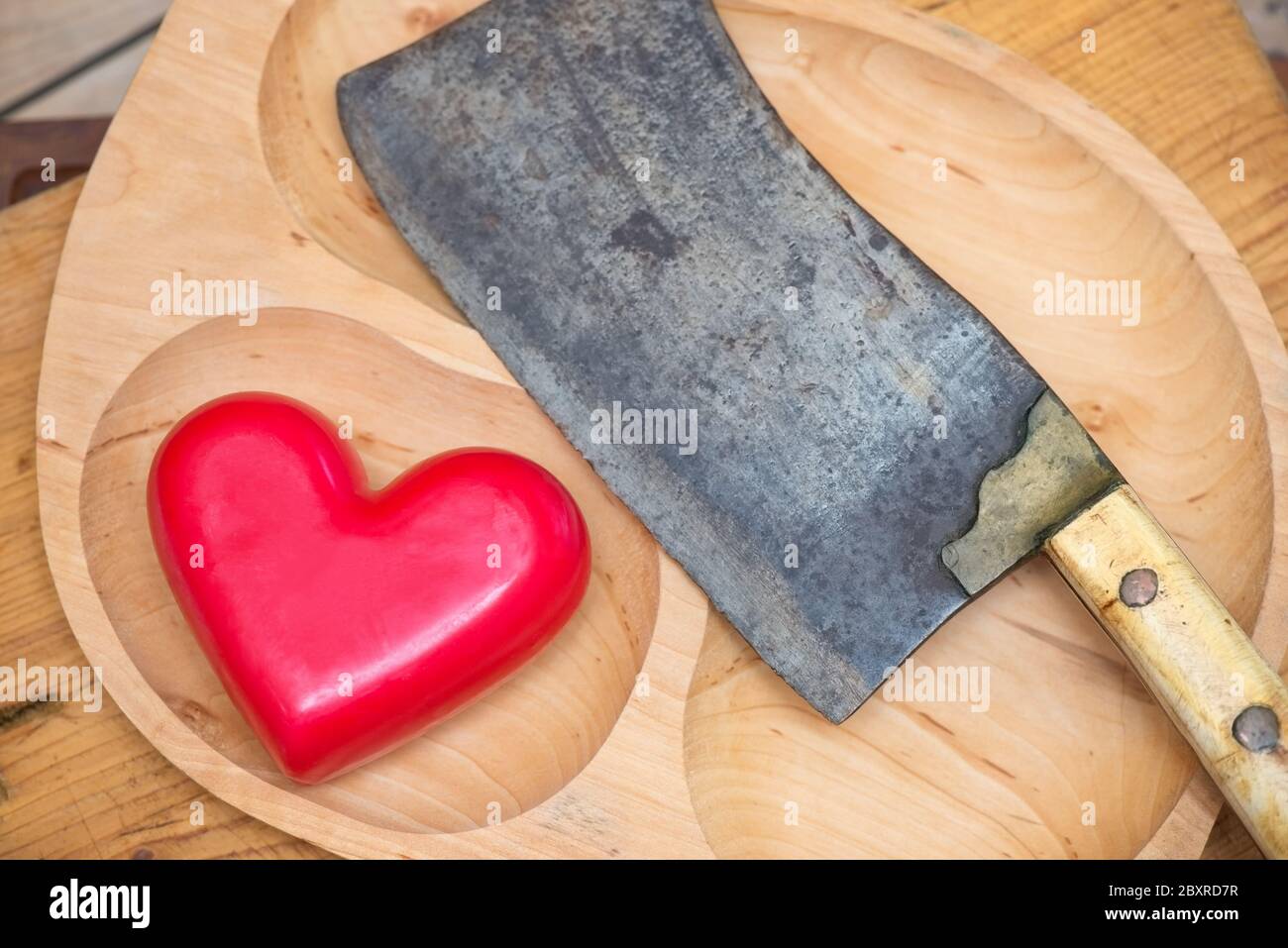Meat cleaver and heart on a wooden board Stock Photo