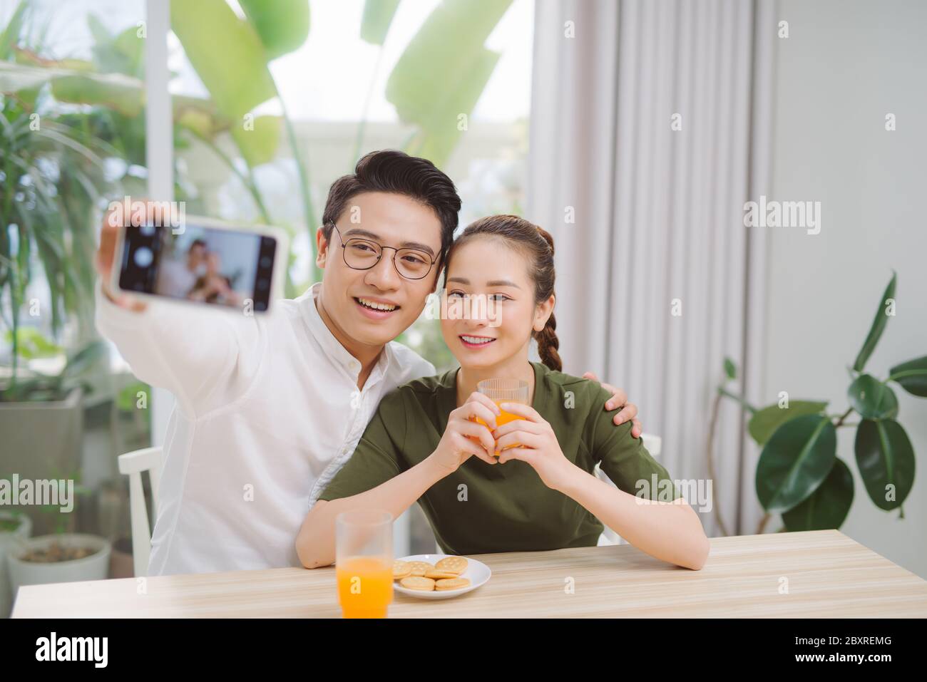 Beautiful young couple making selfie ,using a smart phone and smiling while sitting in their apartment Stock Photo
