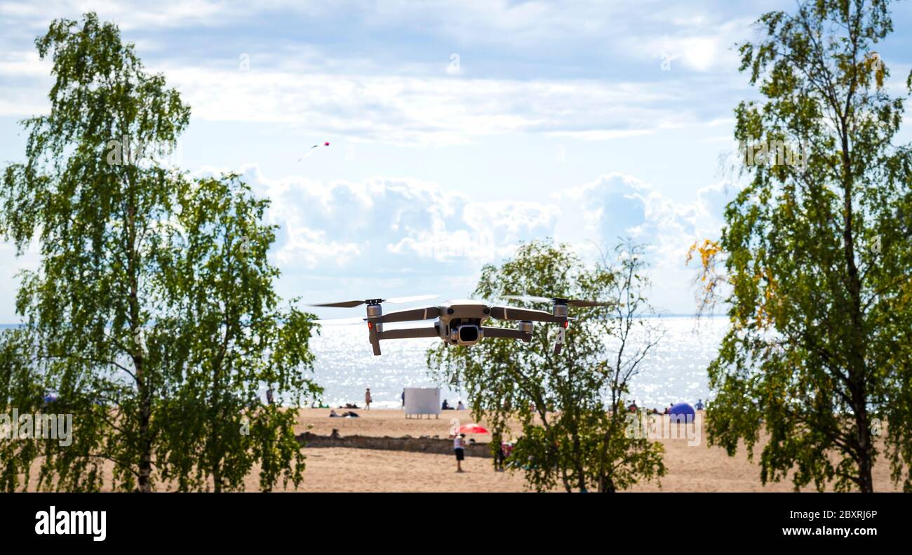 Modern Drone hovering in nature on the seashore over the beach and blue sky Stock Photo