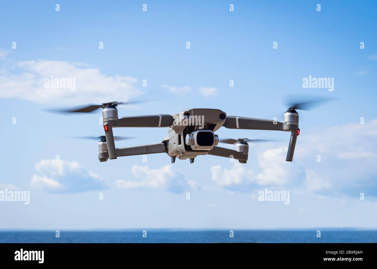 Modern Drone hovering in nature on the seashore over the beach and blue sky Stock Photo