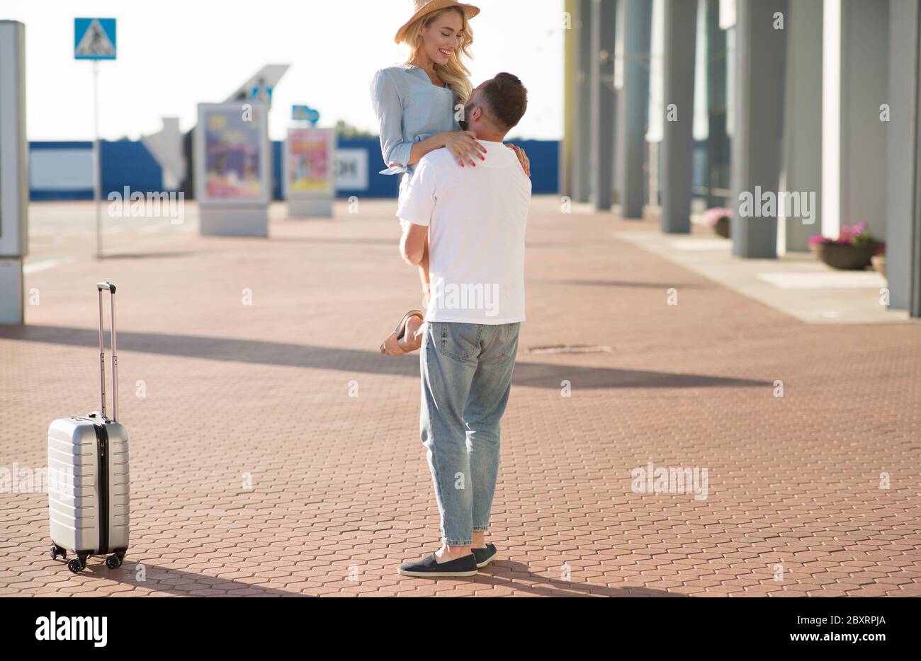 boyfriend-picking-up-his-girlfriend-near-airport-building-stock-photo