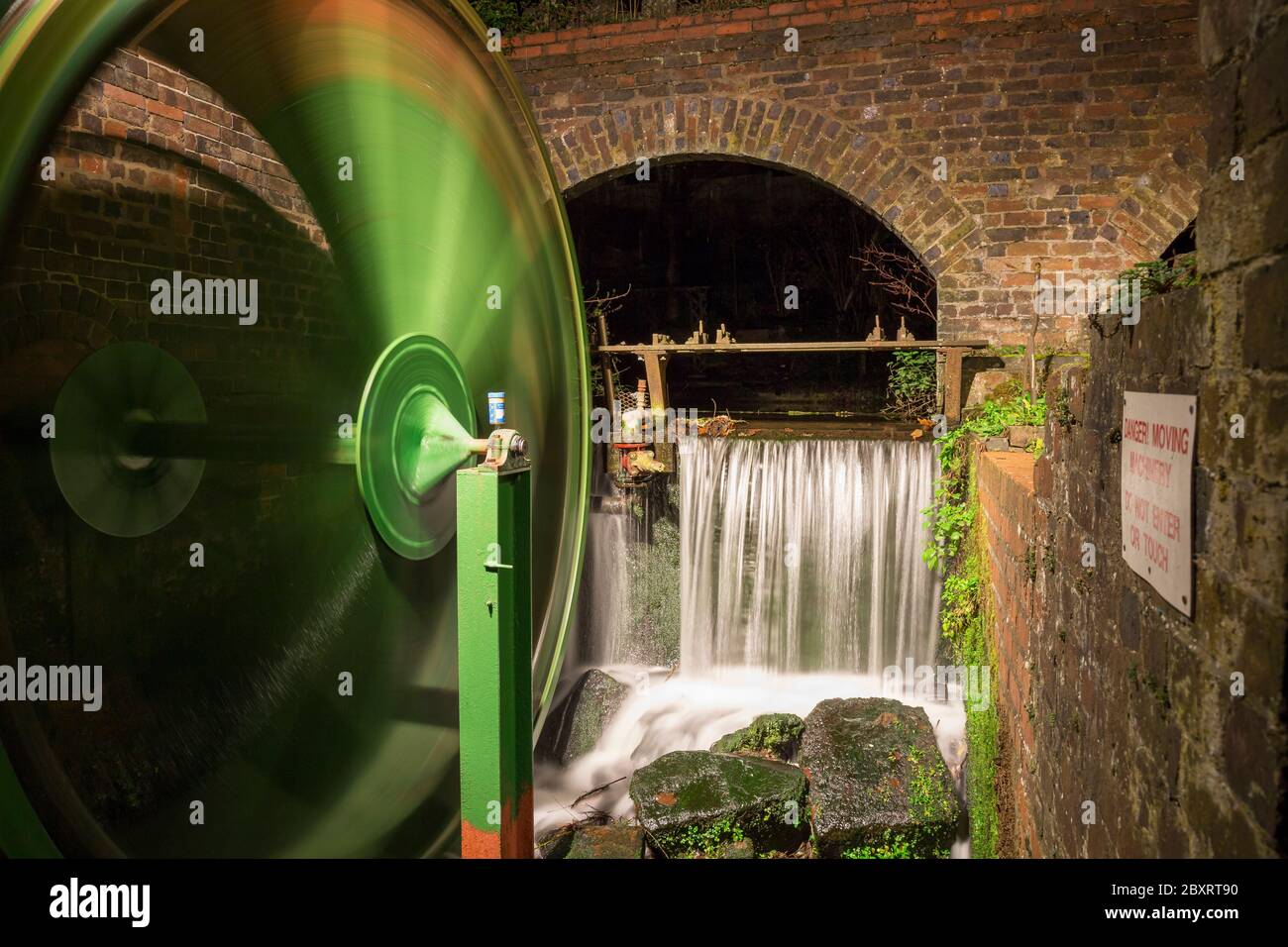 Night view of lit up moving waterwheel, UK. Stock Photo