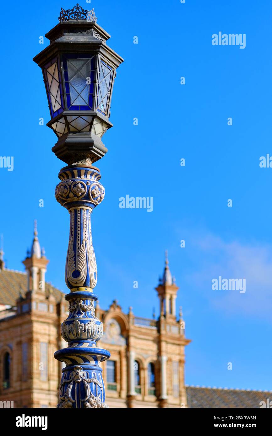 Ceramic tiled lantern and Plaza de Espana ancient architecture on background against blue sky. Beloved famous touristic place, main landmark Sevilla Stock Photo