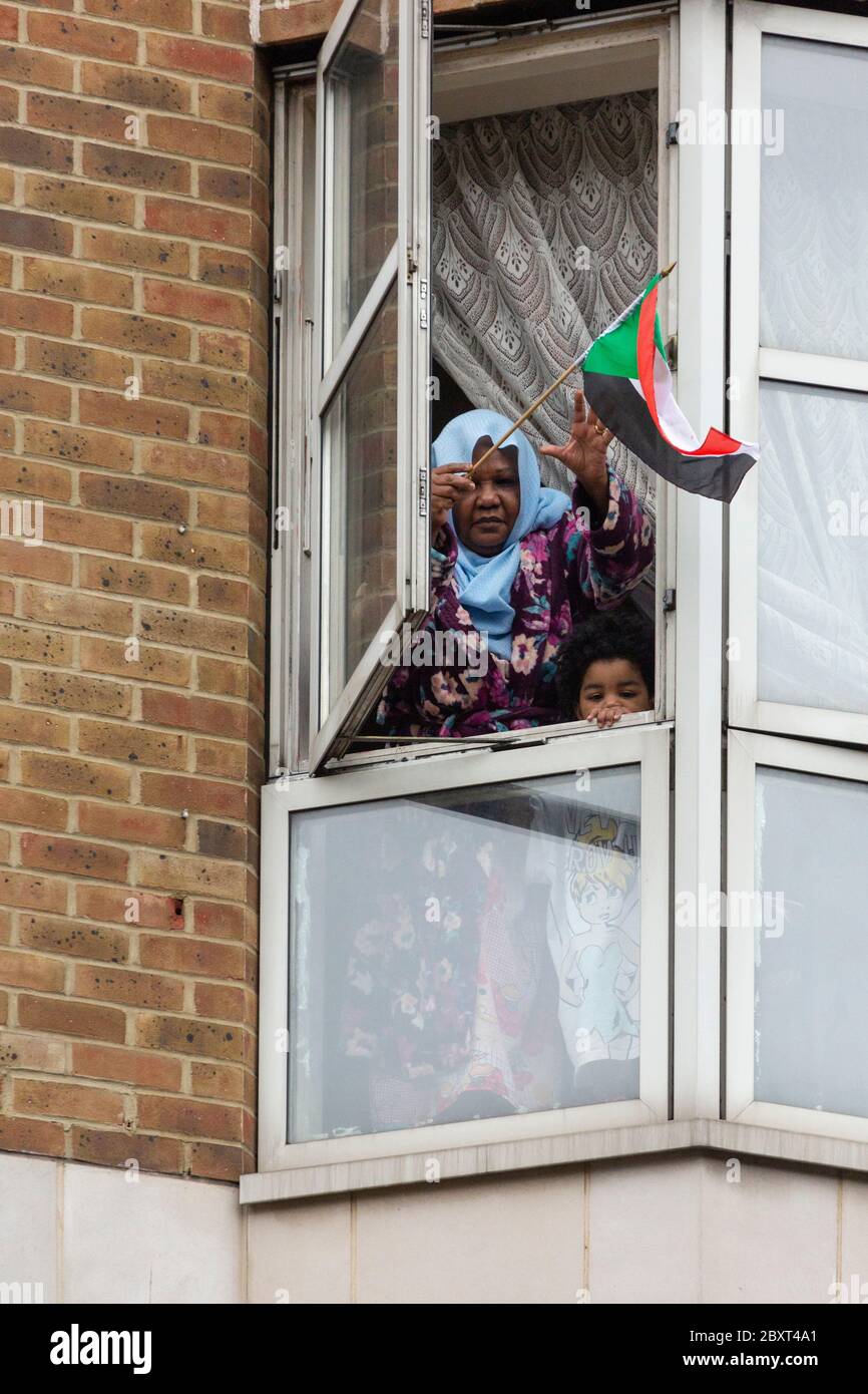 A woman and child lean out their window to wave a flag in support of the Black Lives Matters protest on Vauxhall Bridge Road, London, 6 June 2020 Stock Photo