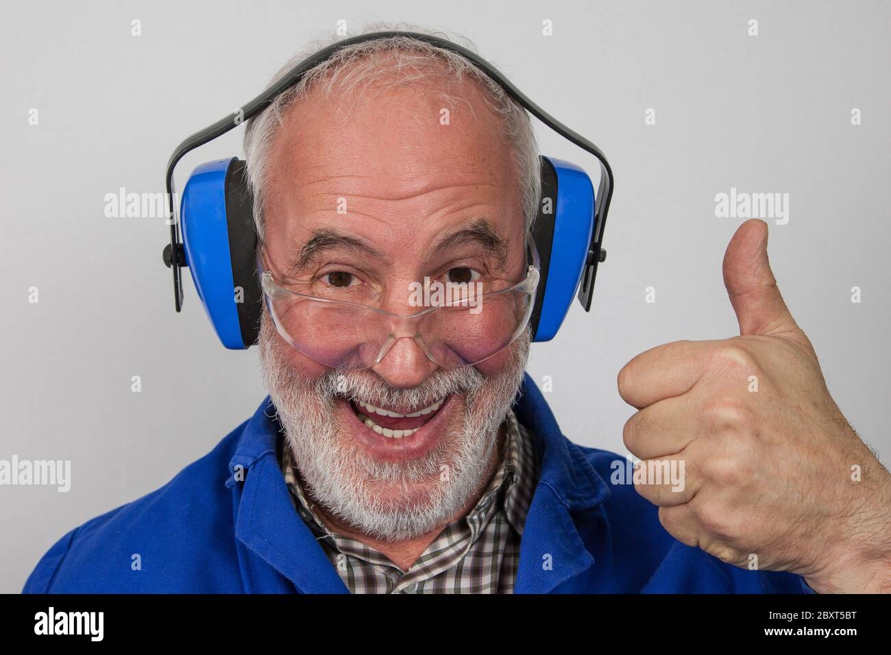 Laughing, old, experienced craftsmen always play it safe and put on hearing protection and safety glasses. Stock Photo