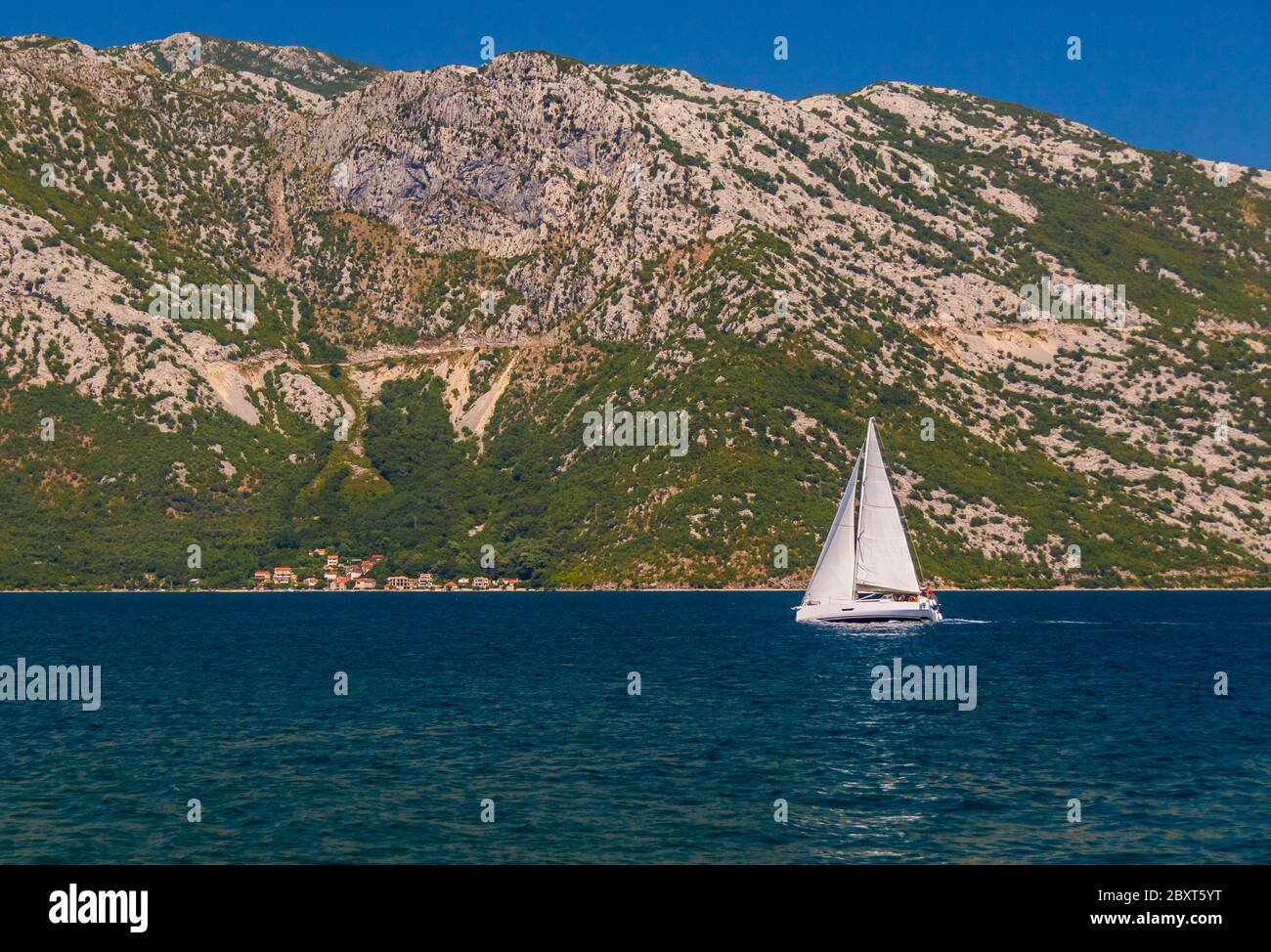 yacht sailing on Bay of Kotor with mountainous backdrop Stock Photo