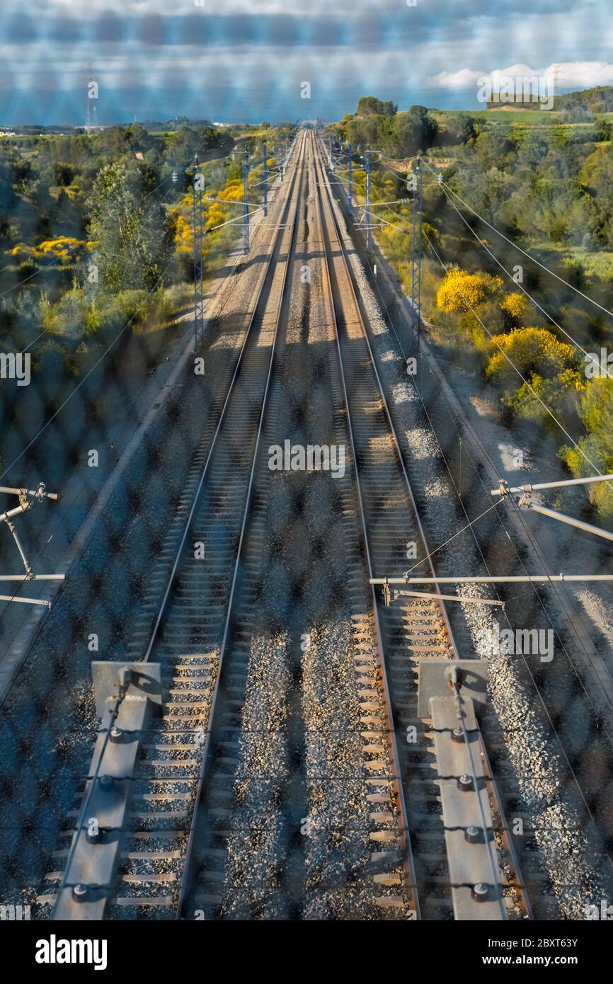 Train tracks located between the mountains, seen from the bridge through the gate. Depth and path concept. Stock Photo