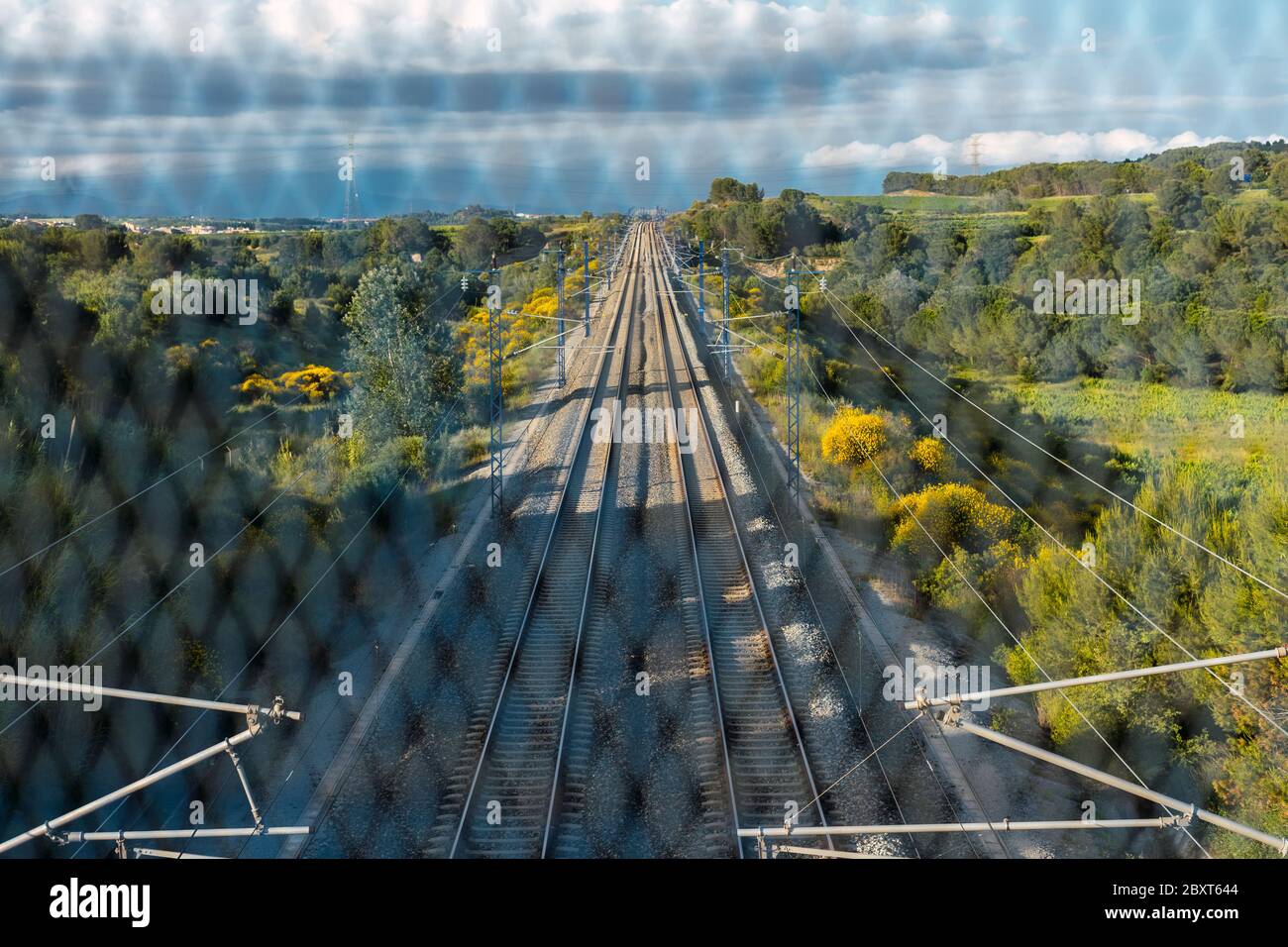 Train tracks located between the mountains, seen from the bridge through the gate. Depth and path concept. Stock Photo