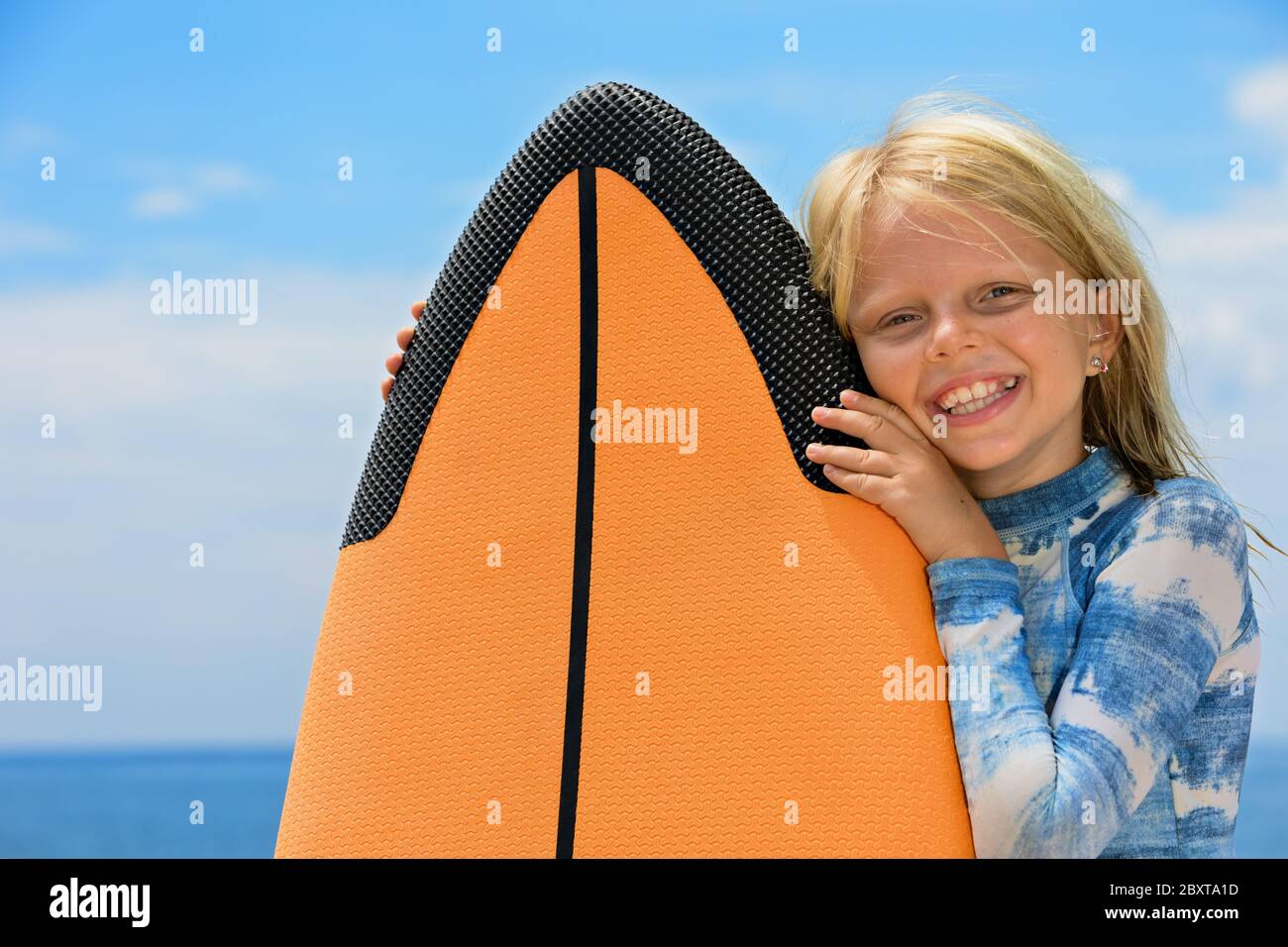Happy baby girl - young surfer learn to ride on surfboard with fun on sea waves. Active family lifestyle, kids outdoor water sport lessons, activity Stock Photo