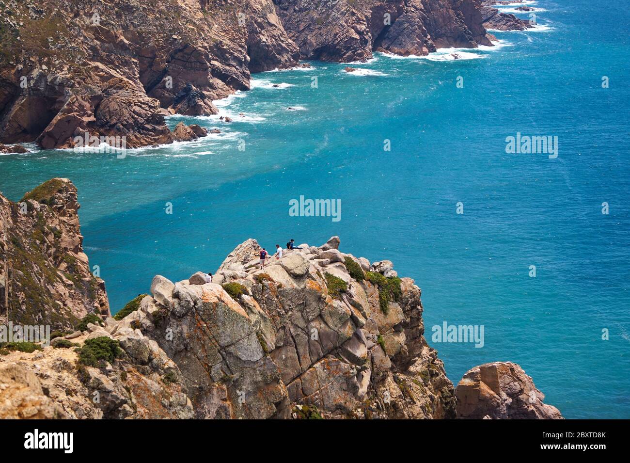 Amazing view of Cabo da Roca and tourists climbing on the cliff with turqoise ocean as a background during sunny day Stock Photo