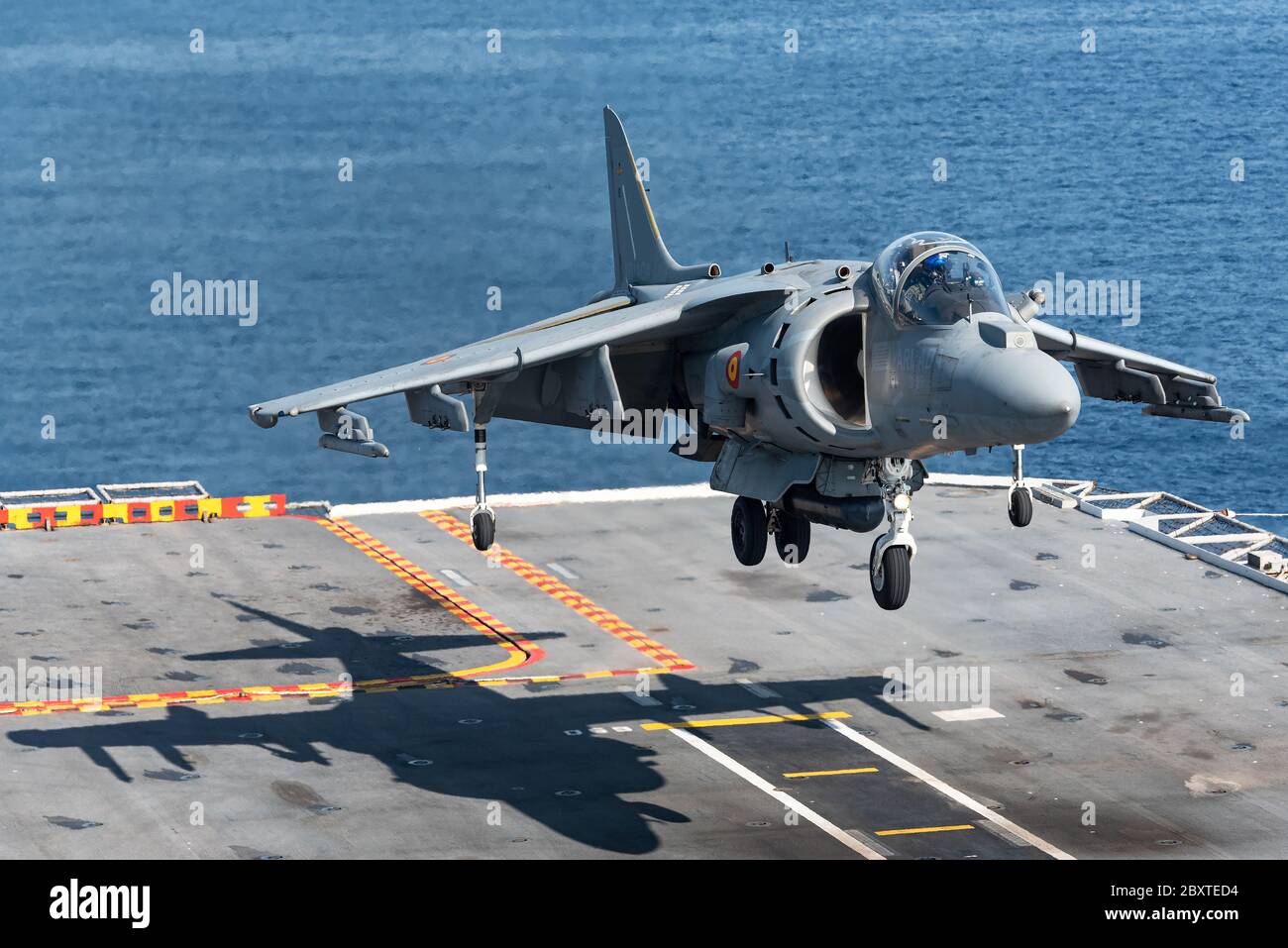 A McDonnell Douglas AV-8B Harrier II fighter jet of the Spanish navy is ready to land at the Juan carlos I aircraft carrier of the Spanish navy. Stock Photo