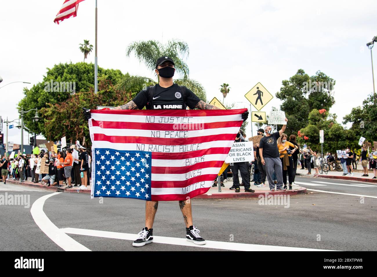 Man carrying an upside down American flag at a peaceful protest honoring George Floyd in Los Angeles, CA Stock Photo