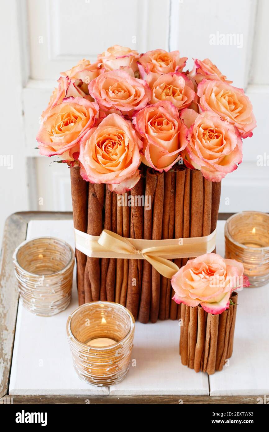 Floral arrangement with roses and cinnamon sticks stands on the table