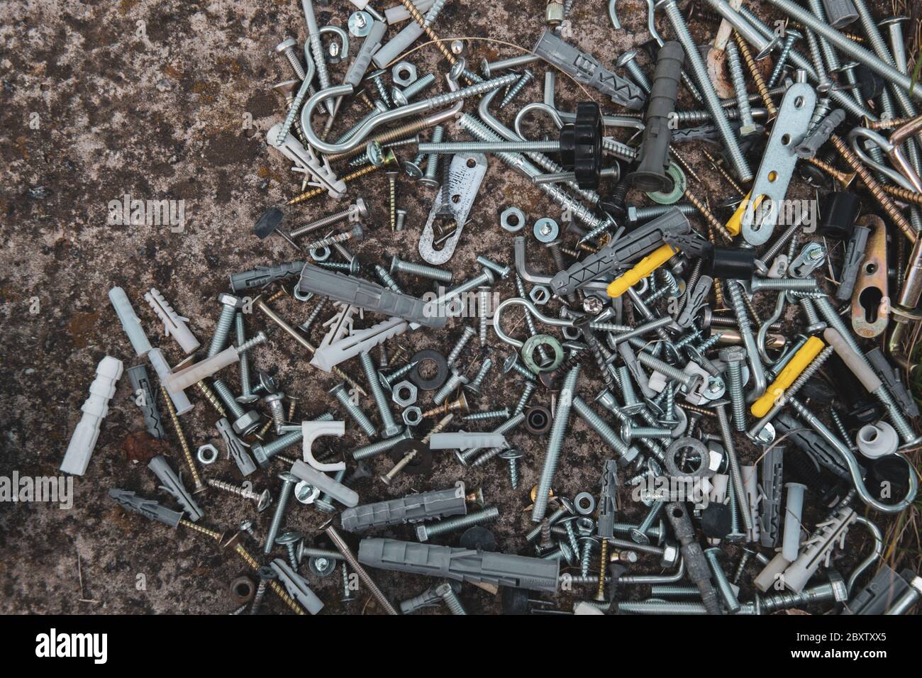 Flat lay of steel bolts and nuts, hooks and dowels on grunge stone