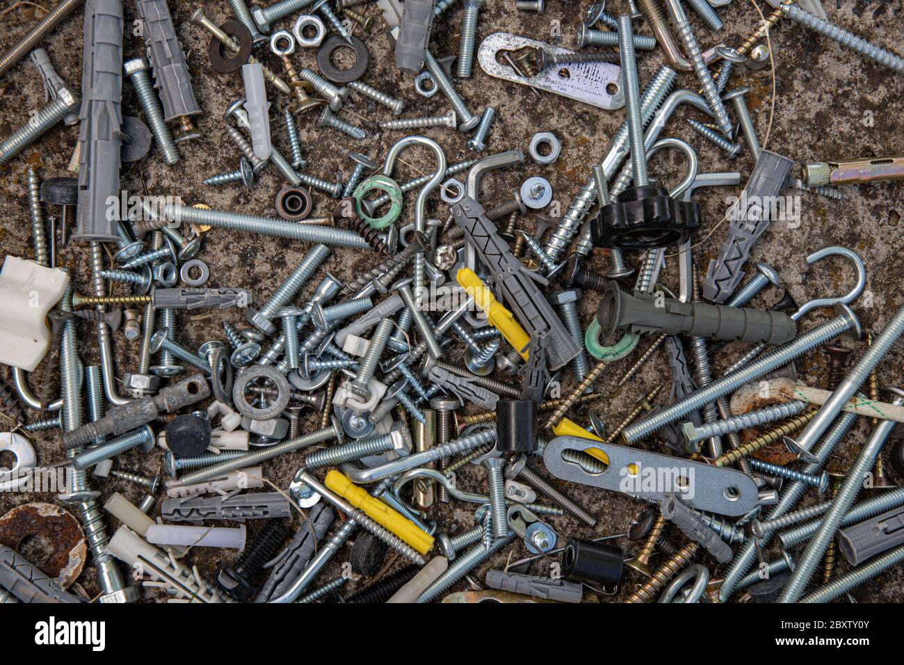 Pile of steel bolts and nuts, hooks and dowels on grunge stone