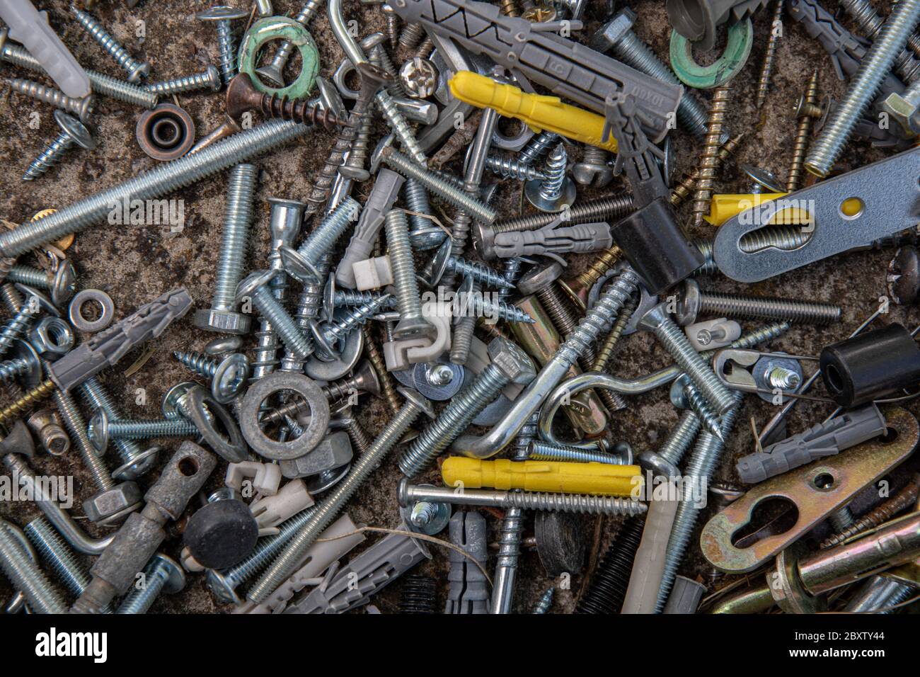 Old steel bolts and nuts, hooks and yellow dowels on grunge stone