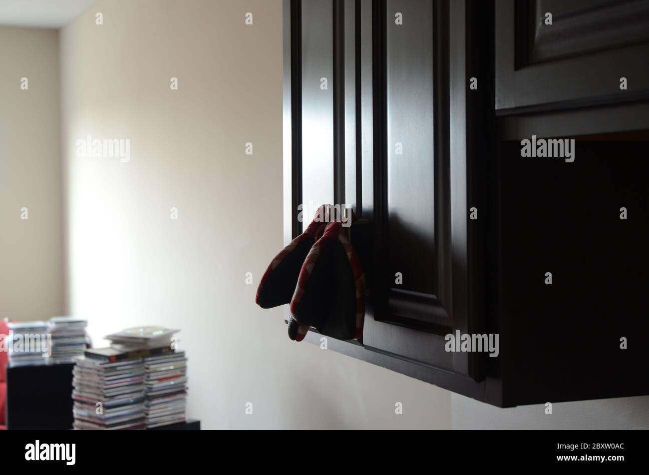 HOME SWEET HOME: A pair of cooking oven mitts hang on the handles of a cabinet door in an apartment. Stock Photo